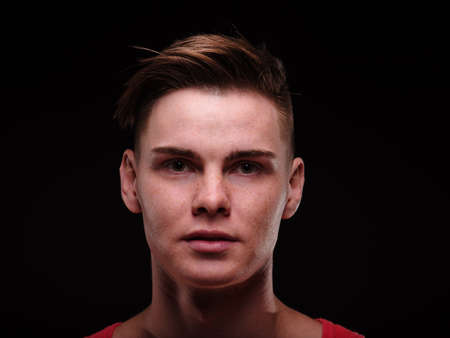 Close-up handsome young man on a black background. Masculine guy. Portrait photography concept.