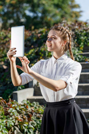 Young girl in the park with a tablet in hand.