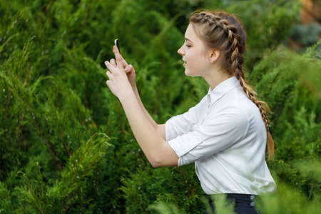 Happy young girl in park with phone in hands.の写真素材