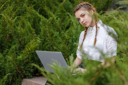 Happy young girl working on laptop in parkの写真素材