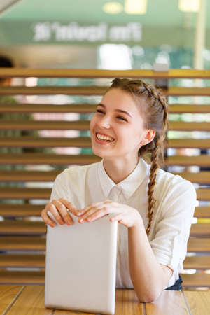 Beautiful girl spends time with gadgets in a cafeの写真素材