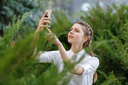 Happy young girl in park with phone in hands.の写真素材