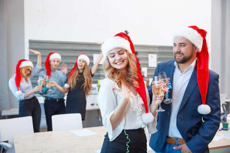 Celebrating colleagues in Santa hats on the office background. Christmas holiday concept. Copy space.の写真素材
