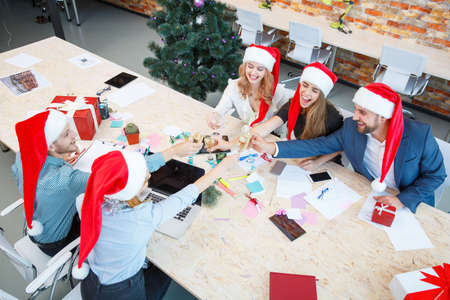 Group of friends clinking glasses and cheering on the office background. Christmas toasting concept.の写真素材