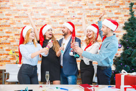 Happy friends in Santa caps drinking alcohol on a blurred background. Christmas and New year concept.の写真素材