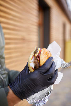 Juisy burger with beef in male hand on the wooden background. Food concept.の写真素材