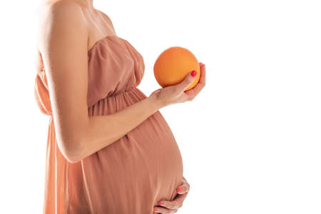 Pregnant woman with orange isolated on a white backgroundの写真素材