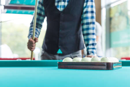 The collected pyramid of balls on the green table cloth in the triangle on the table with the...