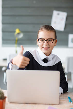 Little businesswoman behind a laptop showing a thumb