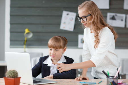 A small businesswoman works at a computer and is helped by an employeeの写真素材