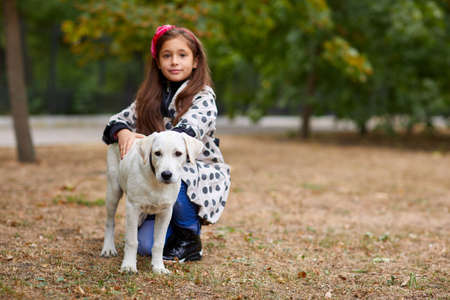 Beautiful young girl playing with dog outdoors. Pet concept.