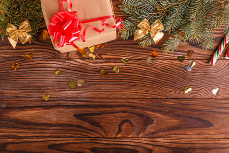 Christmas gift on a wooden brown table. Branches of spruce and confetti. Close-up. Concept of holidays, christmas.の写真素材