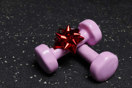 Small dumbbells purple for fitness on a black background with a bowの写真素材