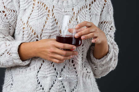 Beautiful girl with a glass of red wine on a black background. The girl with a short haircut. Brunette. Close-up.の写真素材