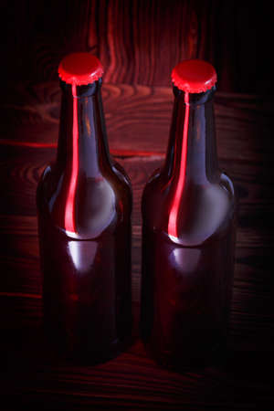 Bottles with beer on a brown wooden background with a red corkの写真素材