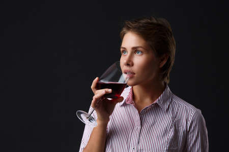 Beautiful girl with a glass of red wine on a black background.