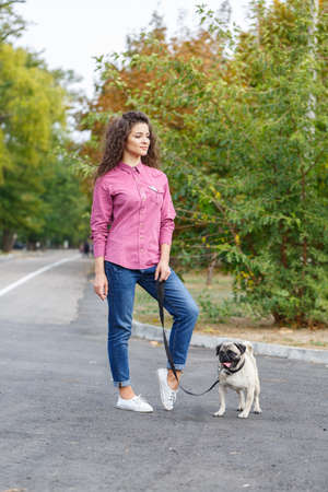 Pretty brunette girl walking with dog in the park. Animal concept.の写真素材