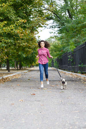 Beautiful brunette girl walking with dog in the park. Animal concept.の写真素材