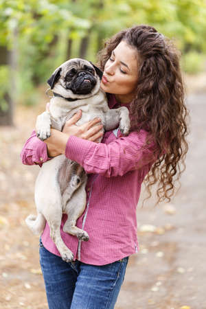 Pretty brunette girl walking with dog in the park. Animal concept.の写真素材
