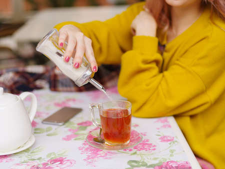 Beautiful young blonde in a yellow sweater at a table in a cafe.の写真素材