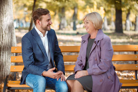 An amazing mother with handsome adult son are happy in autumn park. Family spending time together outdoor.の写真素材