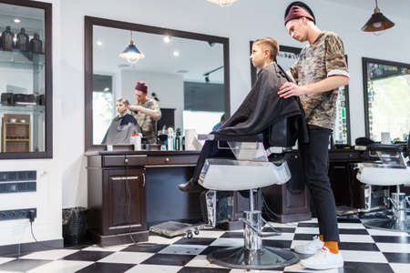 Hairdresser barbershop parihopher strechot small boy sitting on a chairの写真素材