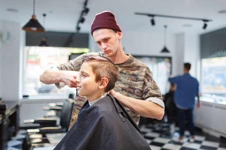 Hairdresser barbershop parihopher strechot small boy sitting on a chairの写真素材