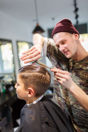 Hairdresser barbershop parihopher strechot small boy sitting on a chairの写真素材