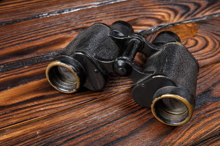 Binoculars on a wooden brown background. Close-up of binoculars. The concept of technology, leisure.の写真素材