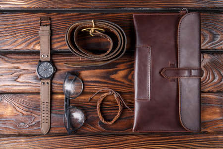 Close-up of a male set on a brown wooden background. Watches, glasses, parthome, belt.の写真素材