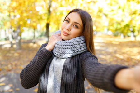 Girl in a black coat on a background of autumn with leavesの写真素材