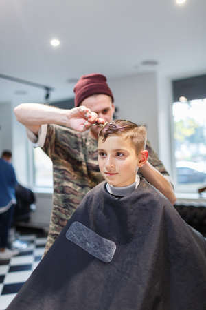 Hairdresser barbershop parihopher strechot small boy sitting on a chairの写真素材