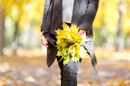 Girl in a black coat on a background of autumn with leavesの写真素材