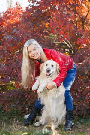 Pretty blonde girl walking with dog in the forest. Animal concept.の写真素材