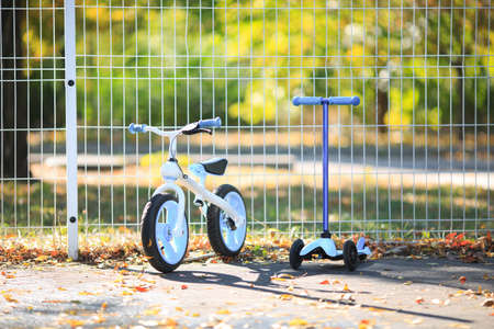 A modern bicycle next to a modern scooter stand on the street in autumnの写真素材