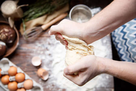 The chef tears the dough over the table. View from above.