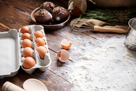 On the table, scattered flour, eggshell and tray with eggs.