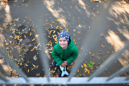 A boy plays in the autumn on the street