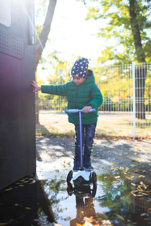 A boy plays in the autumn on the street