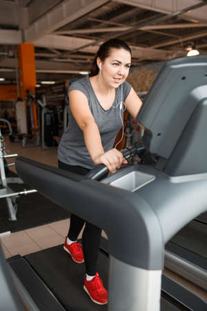 A girl runs on a treadmill and listens to music.