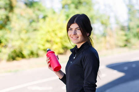 Sporty girl with a bottle for water on the street outdoor