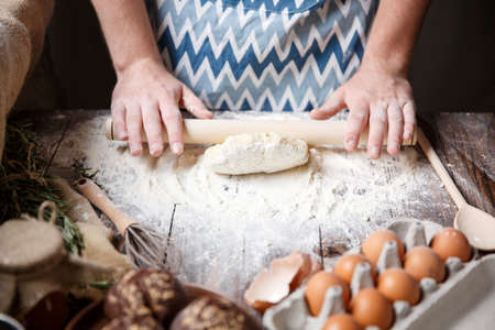 Dough made from wheat flour is rolled on a kitchen table sprinkled with white flour.の写真素材