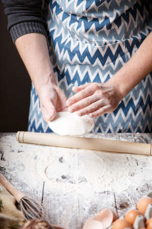 The white cook is holding a small cake of unleavened dough. Indoors.の写真素材