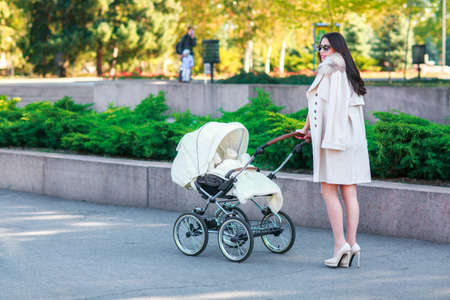 A girl with dark long hair walks with a baby in the park