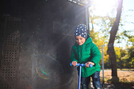 The boy rolls on the scooter and smiles.の写真素材