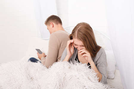 A guy with a gadget and a girl sitting upsetの写真素材