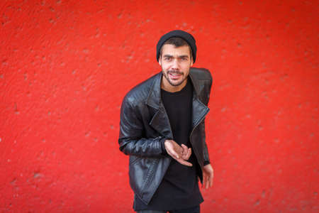 Handsome young man posing on the camera on a red background.の写真素材
