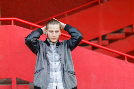 Handsome young man posing on the camera on a red background.