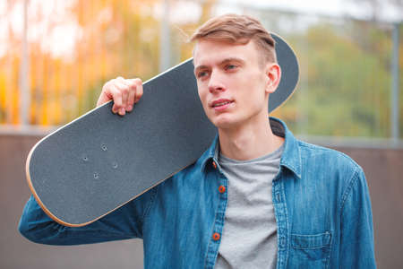 Young skatebarder posing with skateboard in the skatepark. Sport concept.の写真素材