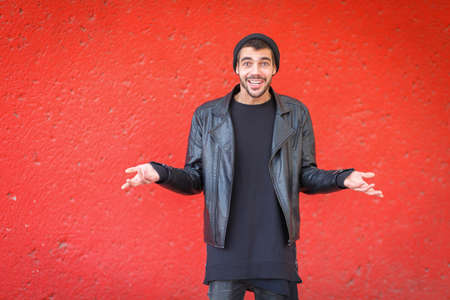 Handsome young man posing on the camera on a red background.の写真素材